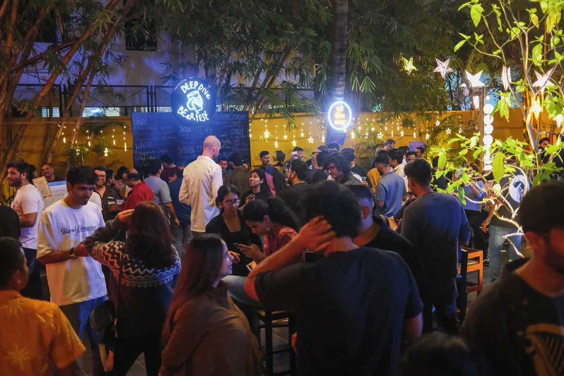 Visitors meet and drink under trees and lights at Deep Dive Beer Fest in Pune.