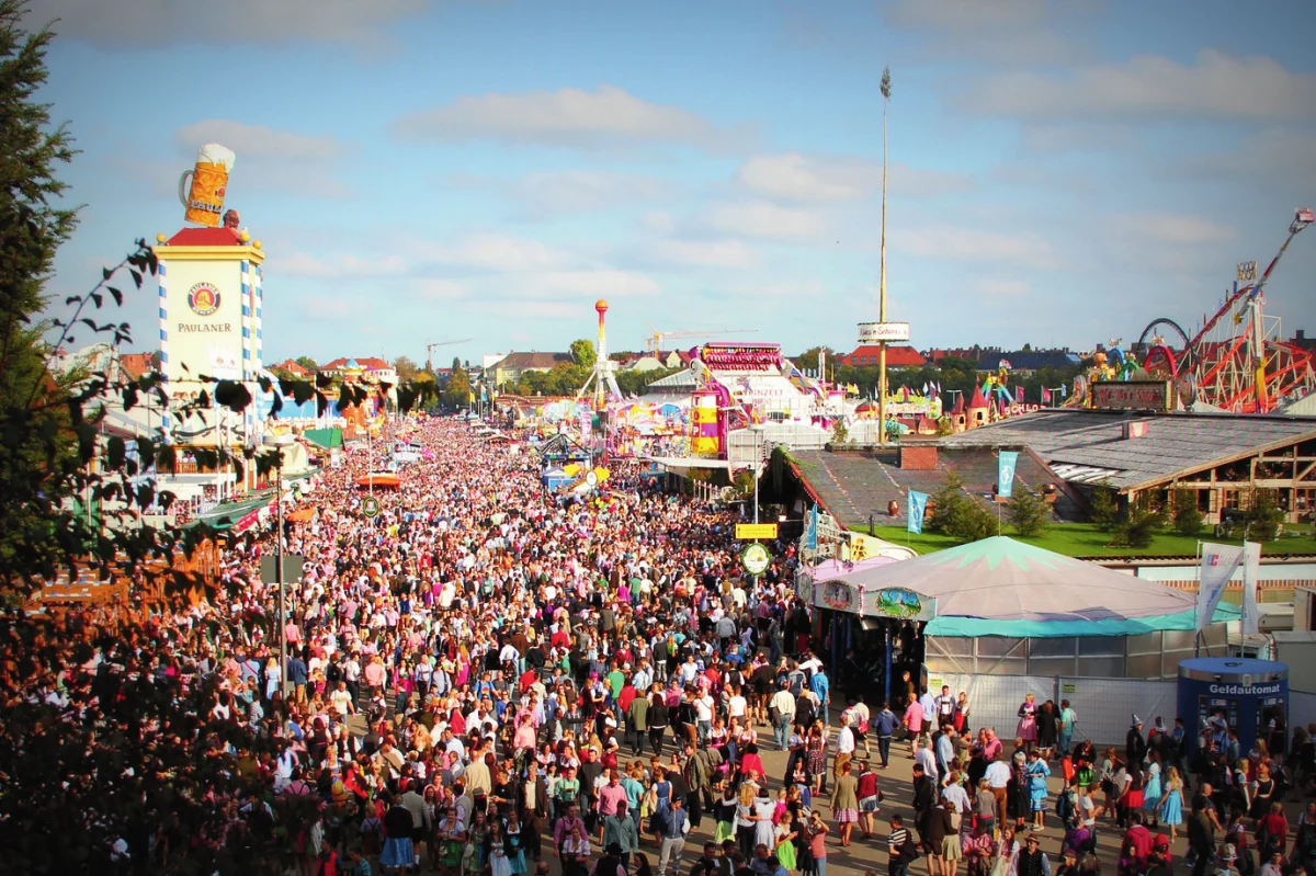 Crowds fill the Oktoberfest grounds in Munich, with beer tents and fairground rides.