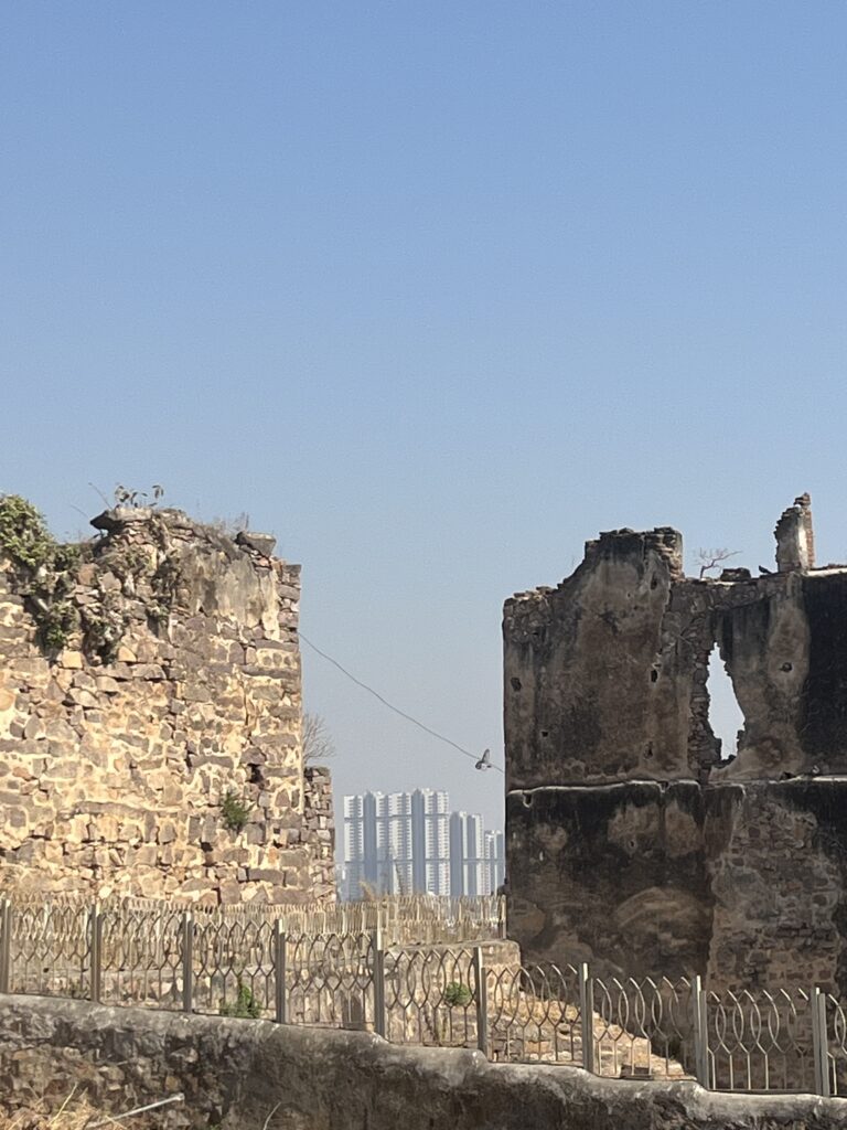 View of skyscrapers through a gap in the old stone walls of Golconda Fort in Hyderabad, India.