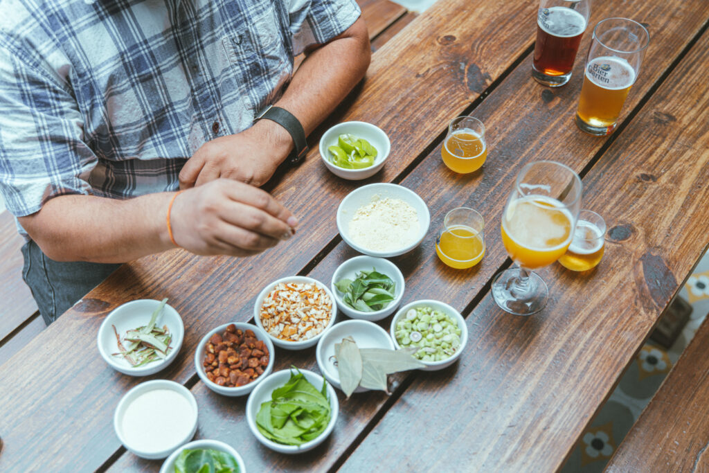 Assortment of bowls filled with Indian botanicals and herbs spread out on a wooden table along with numerous beer tasters at Biergarten Brewery & Kitchen in Bengaluru, India.